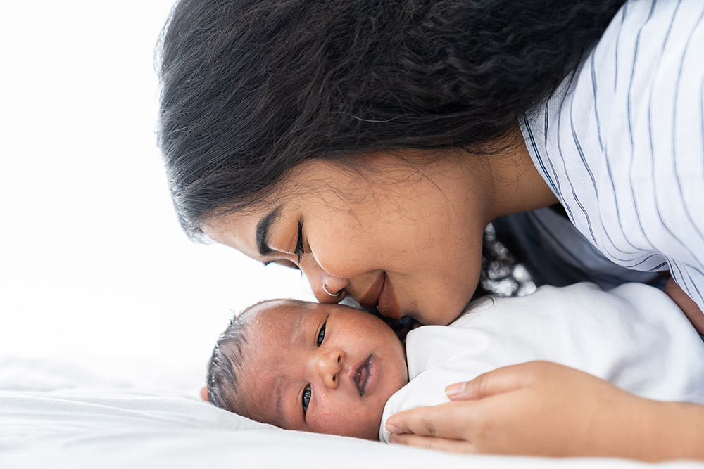 Mother,Kissing,Her,Newborn,Baby,On,The,Bed.,Closeup,Of